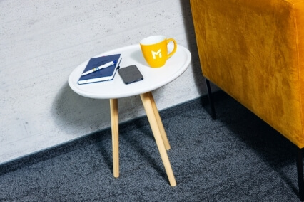 a coffee table, with a yellow mug, a notebook, a pen and a phone