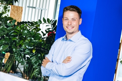 a person standing with crossed arms leaning on a blue column